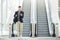 Fashionable happy man on telephone call by escalator