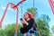 Fashionable happy teenage girl with dyed hair with smartphone riding swing