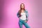 Fashionable happy young woman with lovely smile in stylish youth blue jeans clothes posing and beautiful smiling near vintage pink