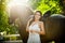 Fashionable lady with white bridal dress near brown horse in nature. Beautiful young woman in a long dress posing with a horse