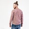 Fashionable man with beard and bun hairstyle dressed in pock-marked long sleeve sweater and jeans poses in the studio on