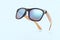 fashionable modern sunglasses with wooden bows isolated on light blue background. Summer sunlight and UV protection