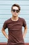 Fashionable modern young hipster man in dark sunglasses in trendy summer t-shirt with stylish hairstyle stands