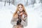 Fashionable modern young woman in stylish winter warm clothes in woolen mittens walks in the winter forest. Beautiful girl