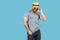 Fashionable muscular bearded emotional man in yellow straw hat posing in studio over blue background