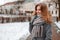 Fashionable pretty young woman with a beautiful smile in a gray elegant coat in a stylish gray scarf in gloves walking around