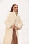 Fashionable self-confident girl in a light faux fur coat. Modern fashion trend for fur coats made of faux fur. Model