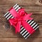 Fashionable striped gift box with a pink bow on board.