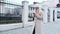 A fashionable student in a white hat and beautiful coat, her newsfeed on her smartphone on her way to university college