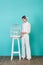 fashionable teen girl in stylish white outfit looking at parrot in cage