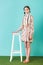 fashionable teen girl in summer dress with braids standing near stool