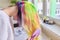 Fashionable teen girl with trendy rainbow dyed hair combing hair at home