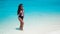 Fashionable Woman in bikini suntanning on tropical beach. Pretty slim girl posing on exotic island by beautiful turquoise ocean.
