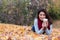 Fashionable woman with coffee lying down on fall leaves