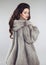 Fashionable woman in mink fur coat over studio gray background.