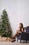 Fashionable woman posing near christmas tree, showing legs in old-fashioned stockings