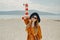 Fashionable woman on vacation against the backdrop of the sea, mountains and a lighthouse. Summer, sunny day, walk along the beach