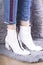 Fashionable woman wear white ankle boots and standing on furry rug.