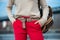 Fashionable women`s casual spring outfit with red pants, cardigan, modern belt and bag