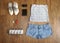 Fashionable women`s look. flat lay feminine clothes and accessories collage: lace top, denim shorts, clutch bag, shoes, camera, li