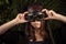 Fashionable young girl in flying helmet on background of tropical leaves