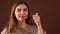 Fashionable young girl showing thumb up on a brown background in the Studio.