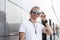 Fashionable young hipster man in stylish white t-shirt stands straightens vintage sunglasses outdoors. Cool American guy blond