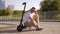 Fashionable young man in sunglasses is sitting on an electric scooter in a Park.