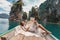 Fashionable young model in boho style dress lying on boat at the lake
