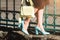 Fashionable young woman in brown dress and blue high heel shoes with yellow handbag in hand on the city streets. Fashion