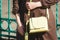 Fashionable young woman in brown dress with yellow handbag in hand on the city streets. Fashion.