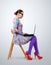 Fashionable young woman in glasses sitting on a chair with a laptop