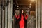 Fashionable young woman with long brunette hair and in red dress stands and looks down