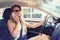 Fashionable young woman talking on mobile phone while driving new car after getting driver`s license