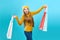 Fashionista girl with bags. Young brunette woman with purchases. Joyful beauty was on sale, on a blue background