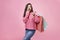 Fashionista girl with bags. Young brunette woman with purchases. Joyful beauty was on sale, on a pink background