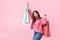 Fashionista girl with bags. Young brunette woman with purchases. Joyful beauty was on sale, on a pink background