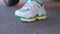 Fashionista wearing white socks and stylish clean sneakers with shiny green lines, puts feet on asphalt of road, gets