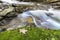 Fast flowing river stream with smooth silky water falling from big stones in beautiful waterfalls on bright sunny summer day