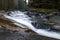 Fast-flowing water, picturesque blurred shapes of the water movement. Rocky shores. Beautiful Stream in the forest.