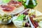 Fast food background closeup. Green olives, sandwiches with jamon, and wooden plate with fuet, chorizo, cheese. Mediterranean fast