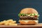 Fast food. Cheeseburger and french fries on a wooden board, on dark background