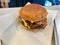 Fast Food Hamburger with Aioli Sauce, Cheddar Cheese, Mayonnaise and Bacon on White Burger Sheet / Street Food Cheeseburger
