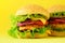 Fast food - juicy hamburgers on yellow background. Take away meal. Unhealthy diet concept with copy space