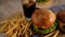 Fast food. Macro, top view of burgers, french fries, cola. A woman made a hamburger from buns, cutlets, lettuce