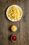 Fast food symbol. French fries on plate on dark wooden table top-down