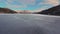 Fast FPV drone flight over a frozen lake with snow-capped sunset mountains in the background