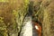 Fast full-flowing foamy water between sandstone rocks, orange sediments on dirty bank. Deep riverbed hewed into block