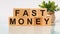 FAST MONEY motivation text on wooden blocks business concept white background. Front view concepts, flower in the background