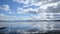 Fast moving cloud layer over majestic mountains and reflective blue fjord water timelapse